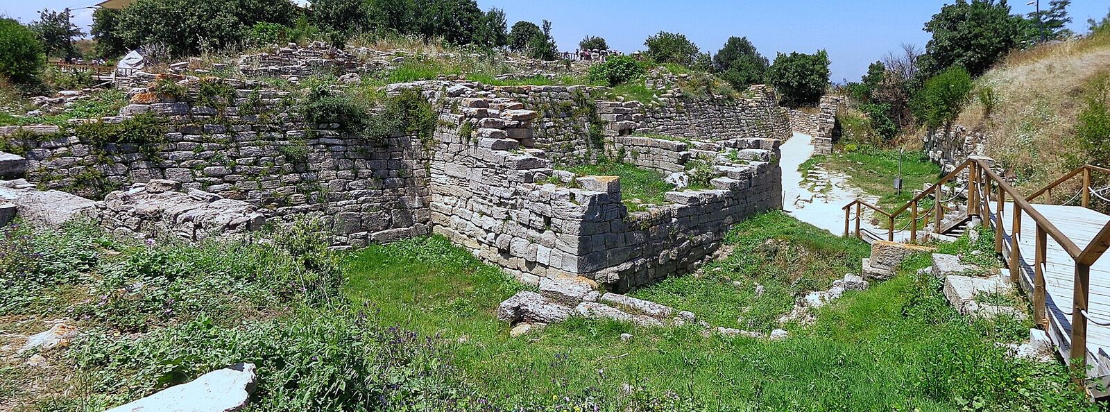 The east gate of Troy VI: sloping limestone wall and the gate passage curving past its foot.